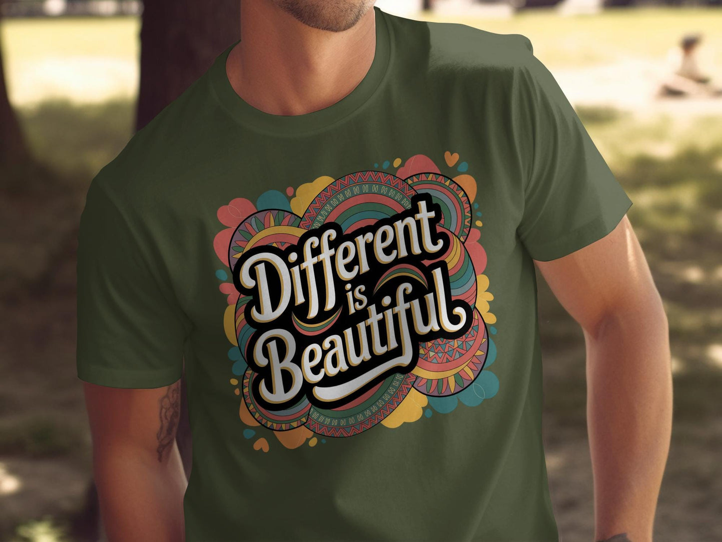 Man wearing a military green t-shirt with a colorful graphic that reads “Different is Beautiful” in bold, retro-style white lettering. The design features swirls and hearts in vibrant teal, pink, mustard, and orange. This bold shirt is a colorful graphic tee and positive quote tee, perfect for those who want a stand out shirt with a custom graphic print. A unique statement tee and inspirational shirt that doubles as a self love t shirt and emotional shirt.