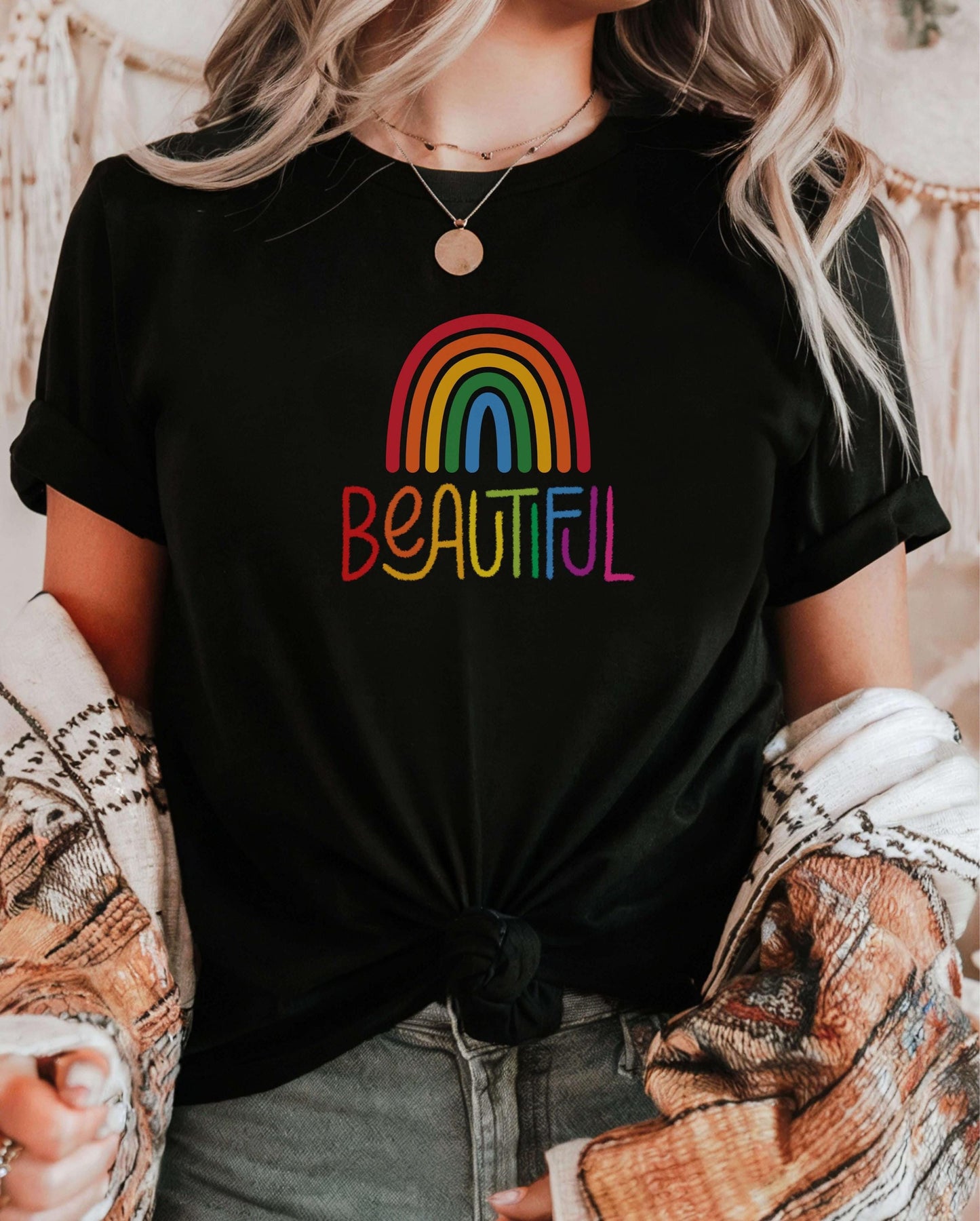 Knotted black t-shirt with rainbow “Beautiful” text, worn with light-wash jeans and cozy cardigan. Affirmation shirt for women, empowering LGBTQ+ shirt, uplifting pride apparel.