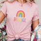Light pink rainbow t-shirt with colorful “Beautiful” text, styled with plaid outerwear. Feminine LGBTQ+ pride tee, pastel pride shirt, rainbow self-love fashion.