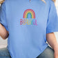 Light blue t-shirt with a rainbow and “Beautiful” printed in bright colors, worn by a woman in jeans. Positive graphic tee, mental health awareness shirt, pastel pride shirt, self-love fashion.