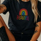 Black rainbow pride t-shirt with “Beautiful” text in rainbow colors, worn by a woman with arm tattoos. Queer fashion shirt, dark aesthetic pride apparel, colorful LGBTQ+ message tee.