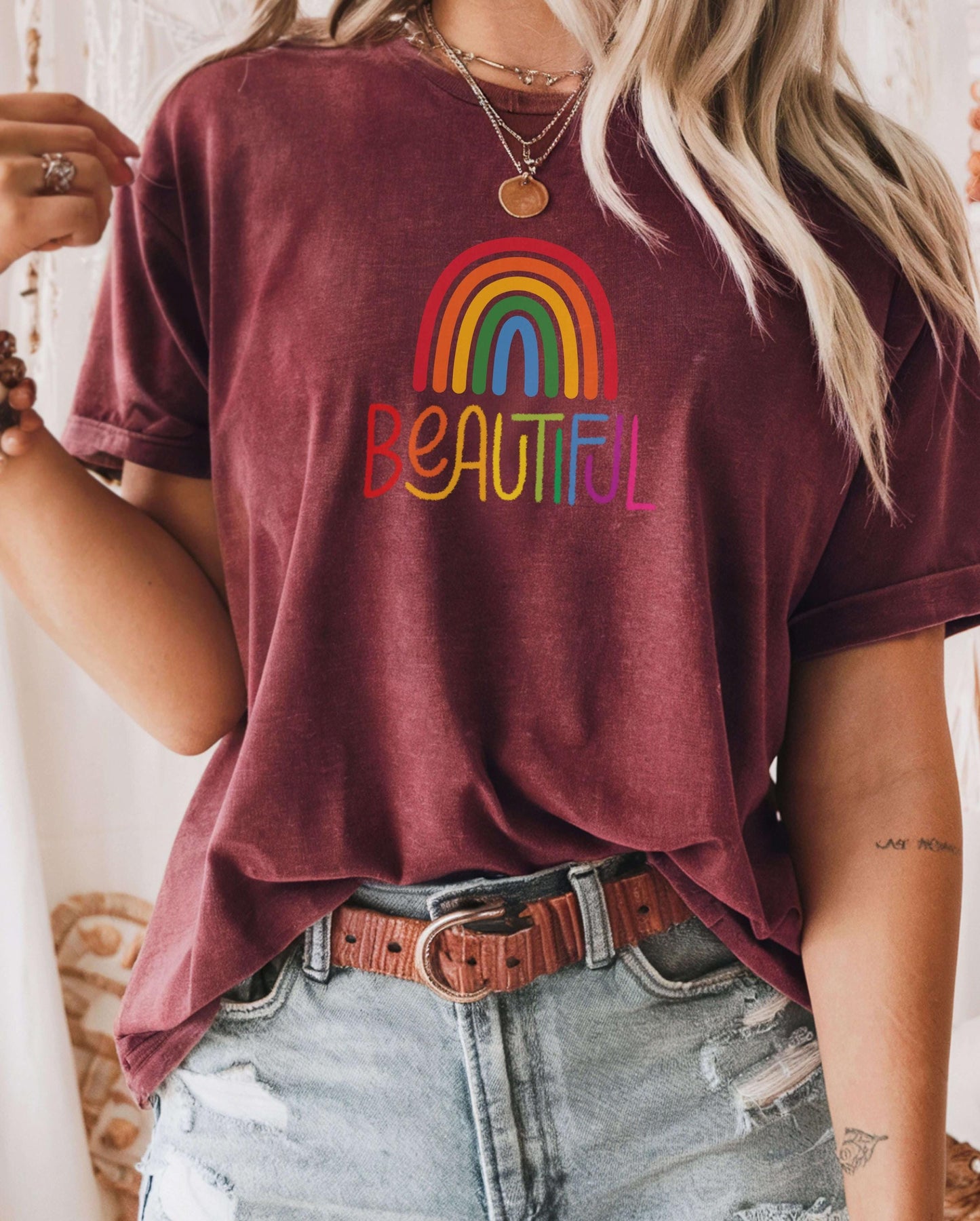 Maroon t-shirt with rainbow “Beautiful” design styled with a leather belt and ripped jeans. Boho rainbow shirt, self-love gift for women, retro inspirational tee, positive quote clothing.