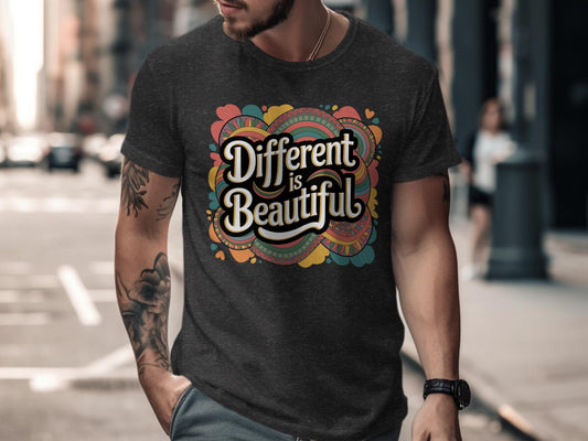 Man wearing a dark heather black t-shirt featuring a bold retro graphic that says &quot;Different is Beautiful&quot; in white vintage-style lettering. The colorful design includes swirling patterns and hearts in orange, teal, mustard, and pink. The shirt has a fitted cut with short sleeves, shown in an urban street setting. A stylish and empowering tee with inclusive, positive vibes.